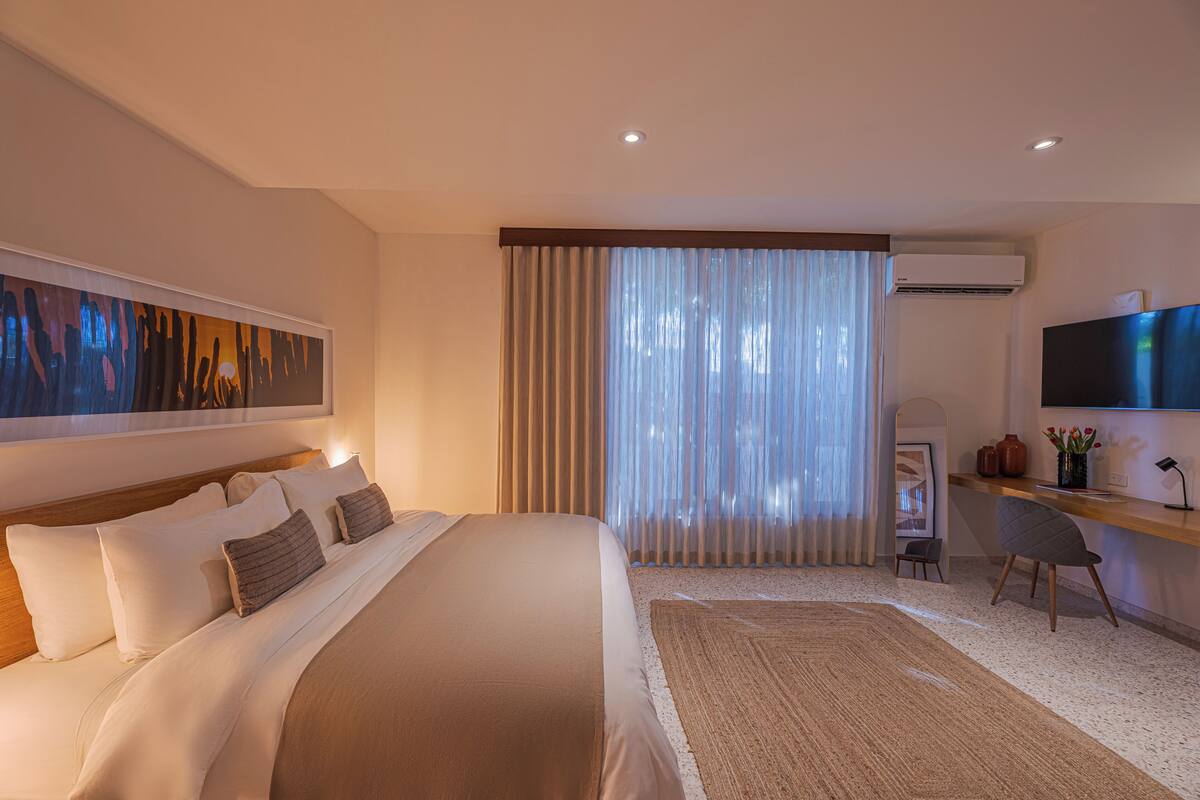 Habitación de hotel con una cama grande, un escritorio con silla, televisión y equipo de aire acondicionado.