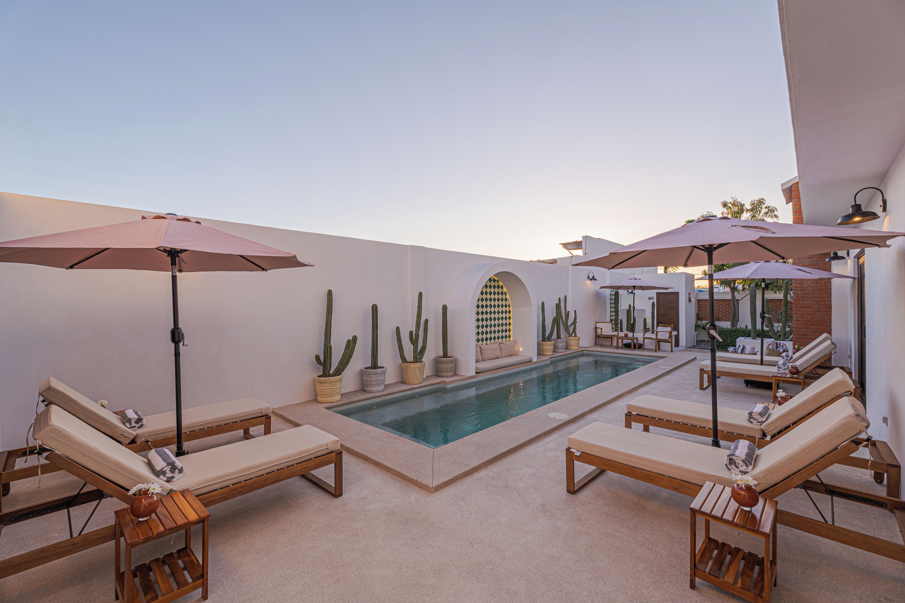 Una piscina al aire libre, sombrillas, sillones reclinables de piscina
