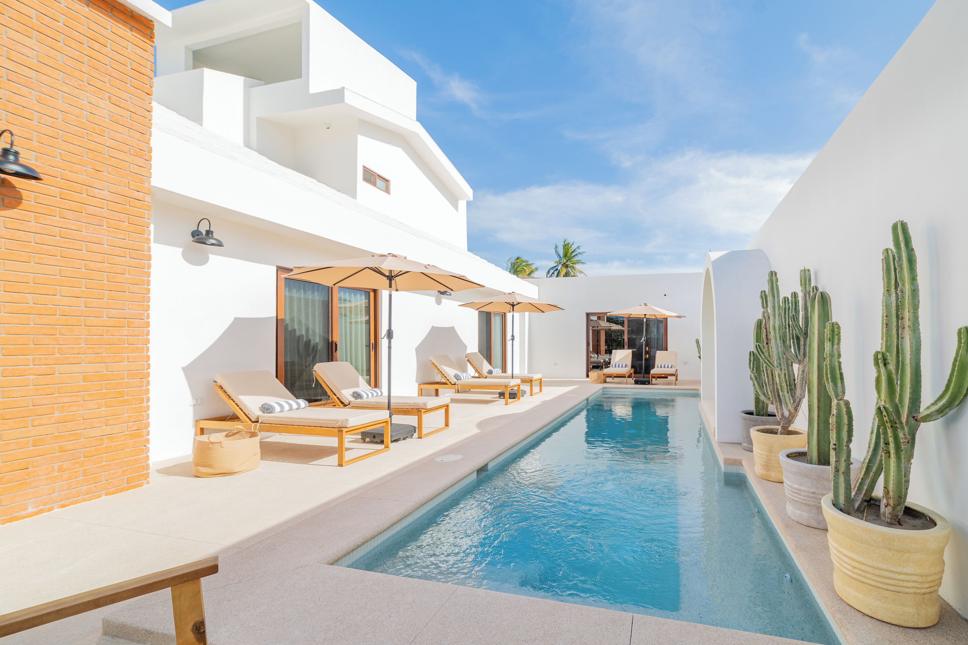 Una piscina al aire libre, sombrillas, sillones reclinables de piscina