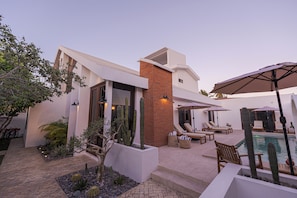 A modern house with a pool, outdoor seating, and cacti.