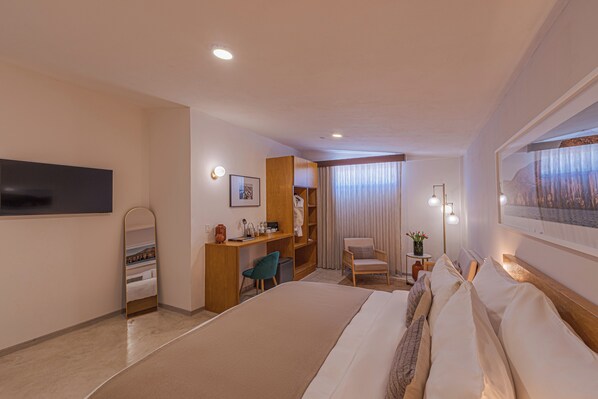 Una habitación de hotel con cama, escritorio, silla y televisor en la pared.