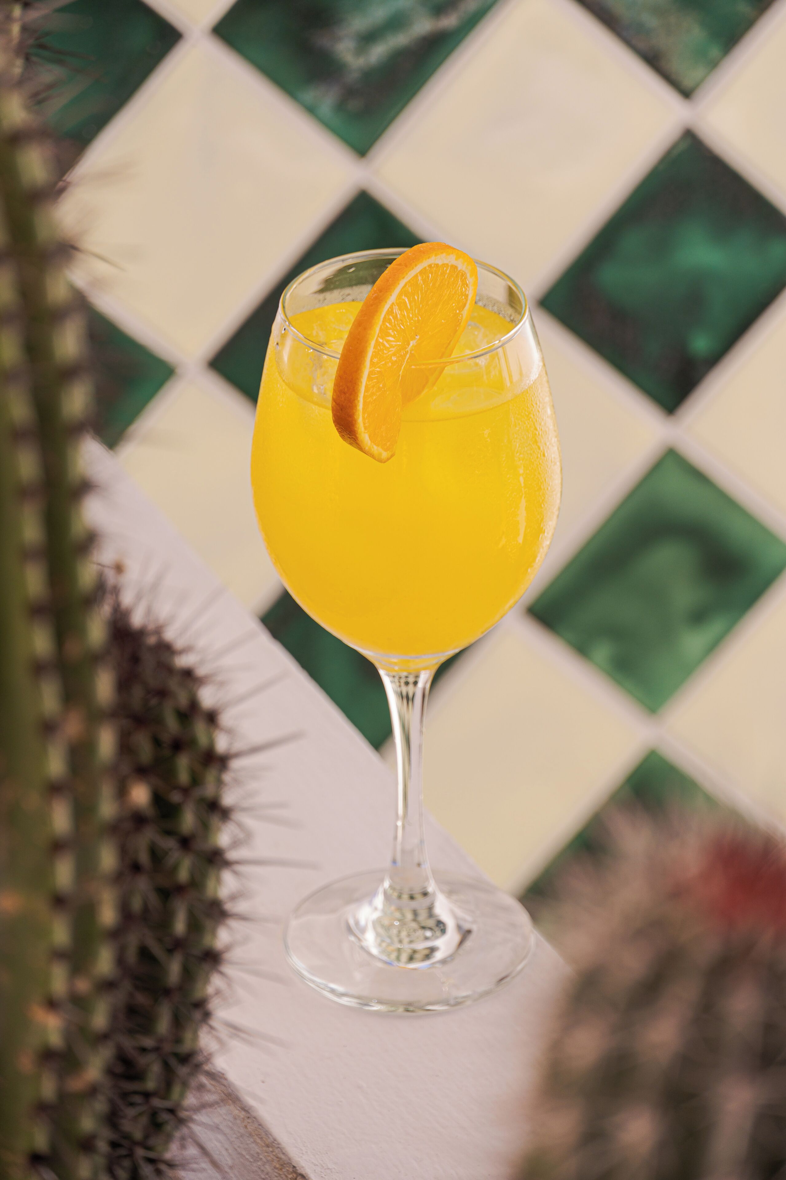 Ett glas apelsinjuice med en apelsinskiva på en vit yta.