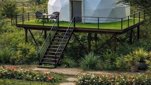Une structure en forme de dôme géodésique, avec un escalier menant à une terrasse dotée de sièges extérieurs.