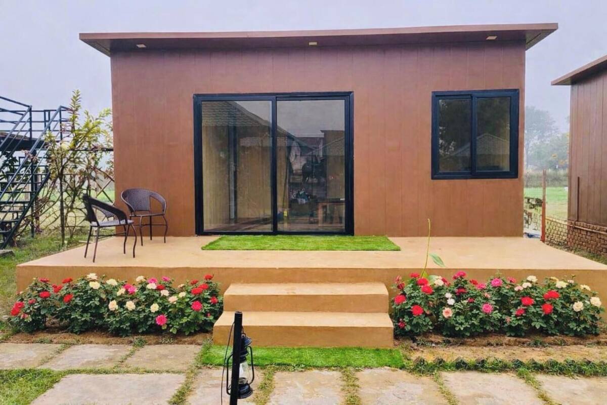 A modern building with a flat roof, large sliding glass doors, and a small outdoor seating area with two chairs.