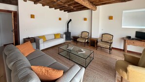 Una sala de estar con sofá, sillones, una mesa de centro de vidrio, chimenea y televisor.