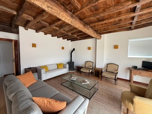 A living room with a sofa, armchairs, a glass coffee table, a fireplace, and a television. - AlcaidariaVista (Ourém)