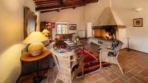 Ein gemütliches Wohnzimmer mit Kamin, Korbmöbeln und einer rustikalen Decke.