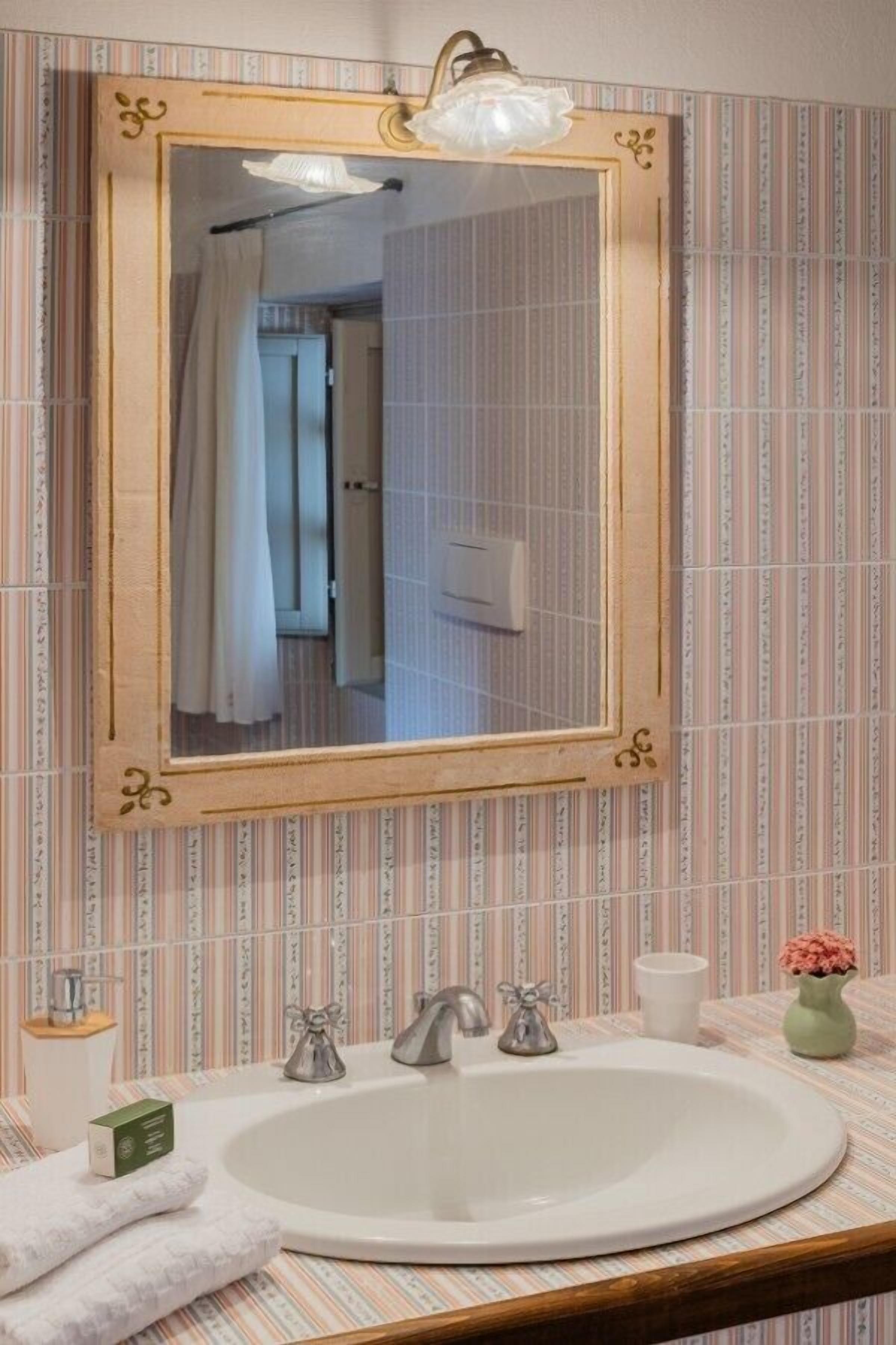 Une salle de bain avec un grand miroir, un lavabo et un rideau de douche.