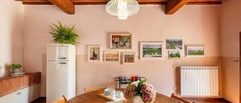 Un comedor con mesa de madera, sillas rojas acolchadas, un refrigerador blanco y una lámpara colgante.
