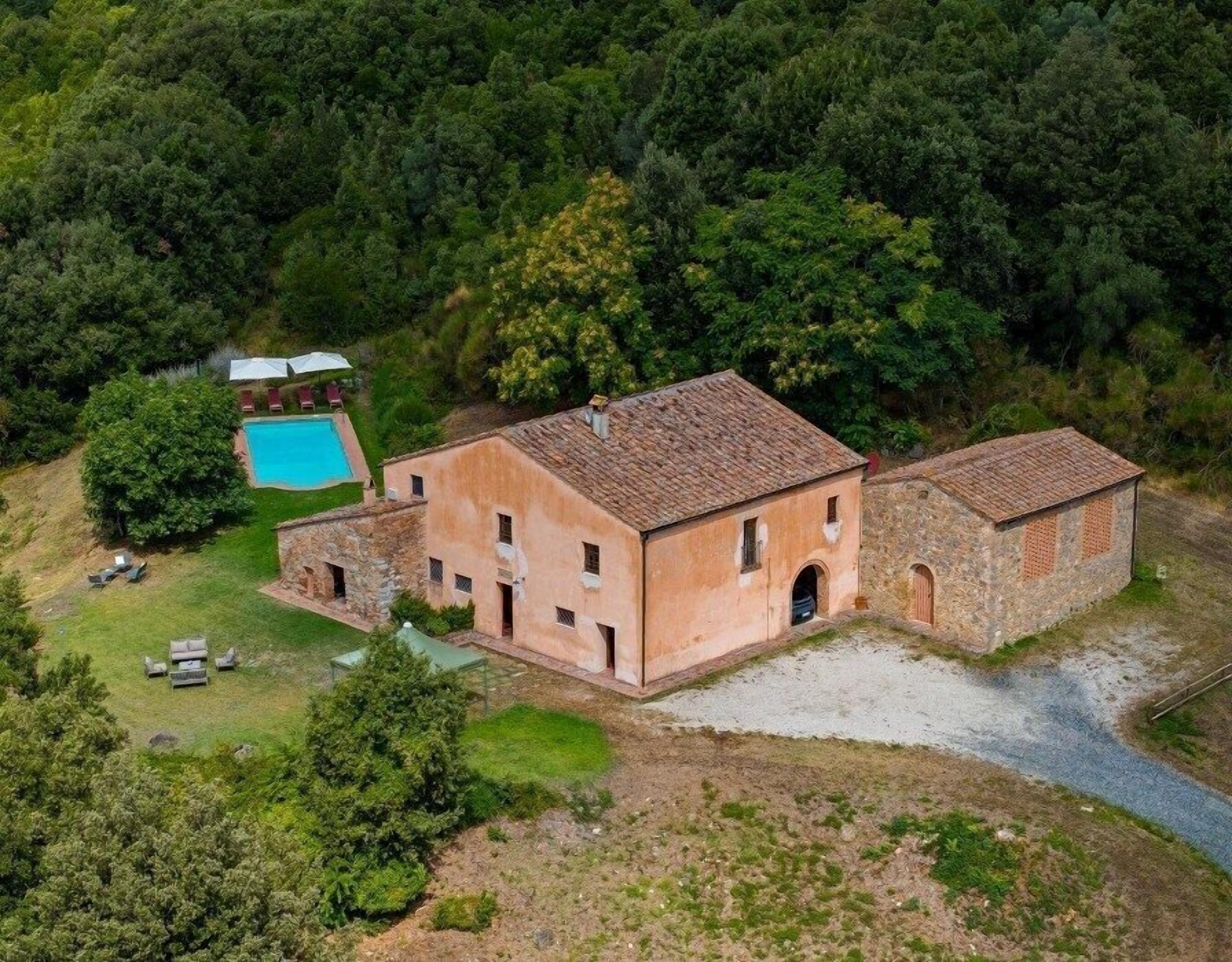 Una villa rústica con piscina, rodeada de un bosque denso.
