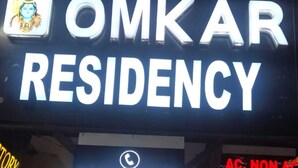 Se ñal de Omkar Residency con un número de contacto y una nota sobre habitaciones disponibles.