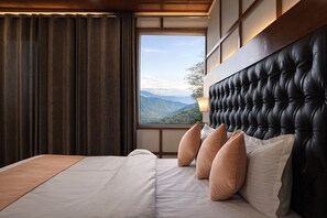 A bedroom with a large window, a tufted headboard, and a view of mountains. - Mussoorie Residency (Mussoorie)