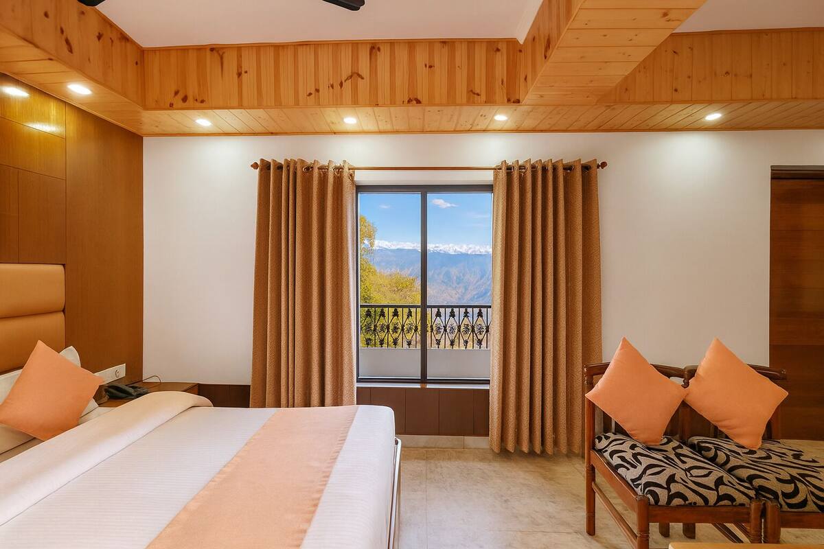 A hotel room with a bed, a chair, and a window with curtains.