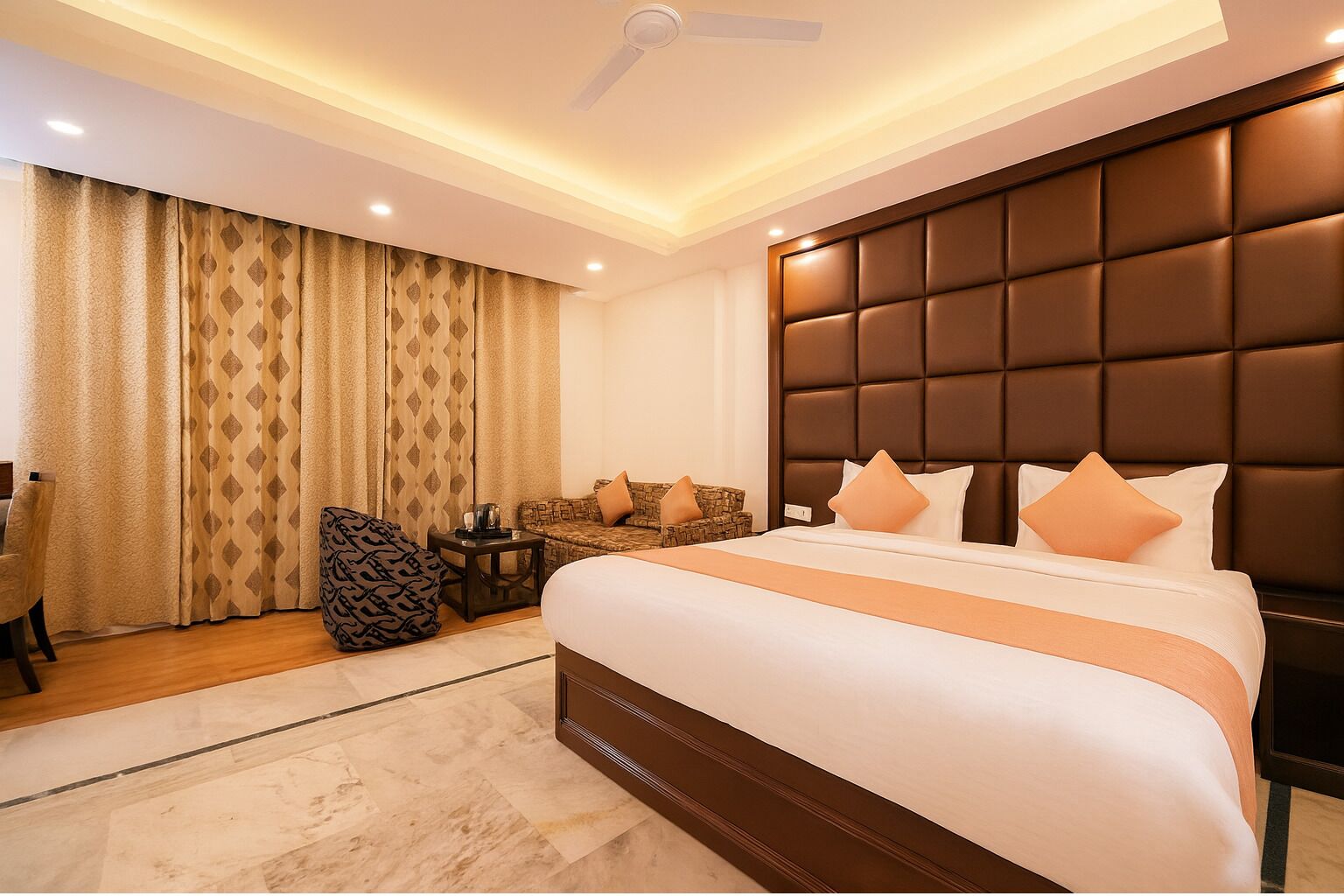 Habitación de hotel con una cama grande, cabecera, sofá, sillón y una mesita.