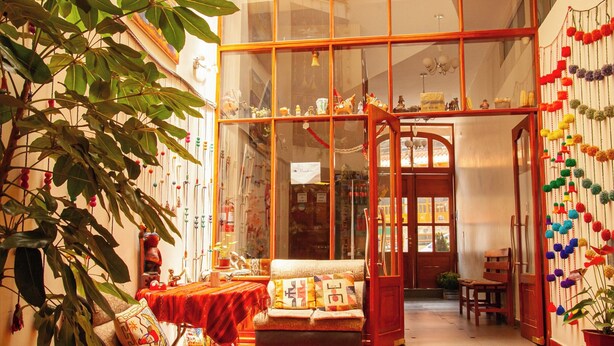 A cozy living room with a large window, a wooden floor, and a variety of decorative items. - Hotel El Chasqui (Ollantaytambo)