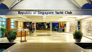 Eingang des Republic of Singapore Yacht Club mit Empfangstresen, Sitzgelegenheit und Topfpflanzen.