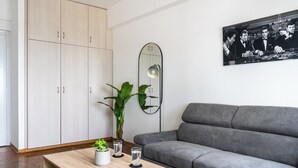 A modern living room with a grey sofa, a wooden coffee table with a plant, and a mirror on the wall. - Bastia - Skyline 1-BR Apt in Nicosia (Nicosia)