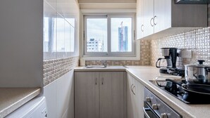 A compact kitchen with a window, a coffee maker, and a stove. - Bastia - Skyline 1-BR Apt in Nicosia (Nicosia)