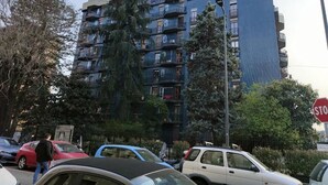 A multi-story residential building with balconies, parked cars, and a stop sign. - Short Rent Milano Porta Vittoria (Milan)