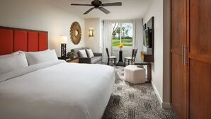 Une chambre d’hôtel dotée d’un grand lit, d’un ventilateur de plafond, d’un coin repas avec une table et des chaises, et offrant une vue sur l’extérieur.