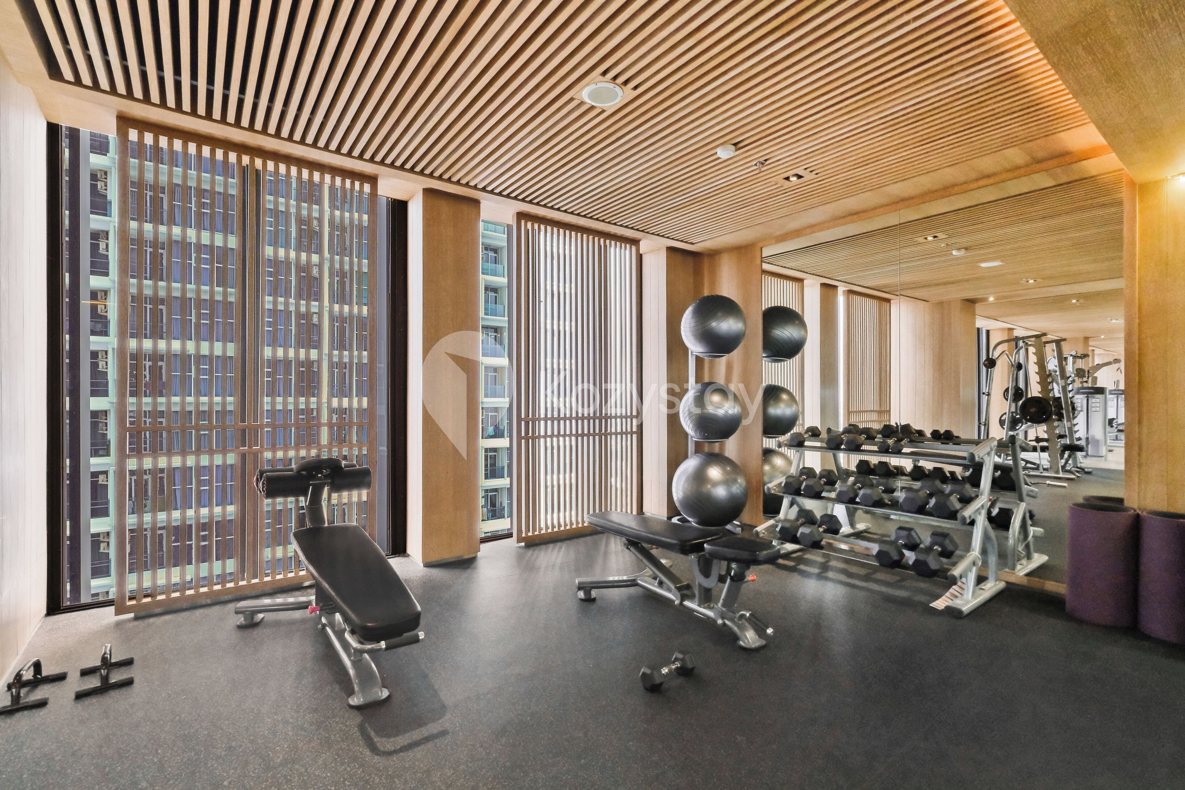 Une salle de sport moderne, dotée d’équipements d’exercice, de grandes fenêtres et d’un plafond en bois.