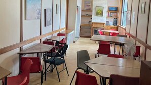 Un comedor con mesas y sillas, un ventilador de techo y obras de arte en las paredes.