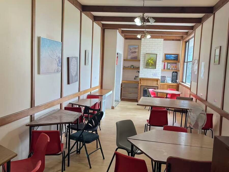 Un comedor con mesas y sillas, un ventilador de techo y obras de arte en las paredes.