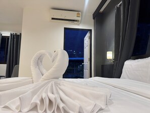 Ein Hotelzimmer mit Bett, Nachttisch, Klimaanlage, Fenster mit Blick und Tür.