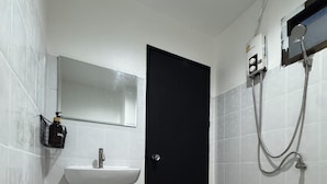 A bathroom with a black door, a white sink, a mirror, and a shower area. - Chapter 26 Guesthouse (Patong)