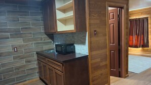 A kitchen with wooden cabinets, a microwave, and a tiled backsplash. - The Mint Motel (Arlington)