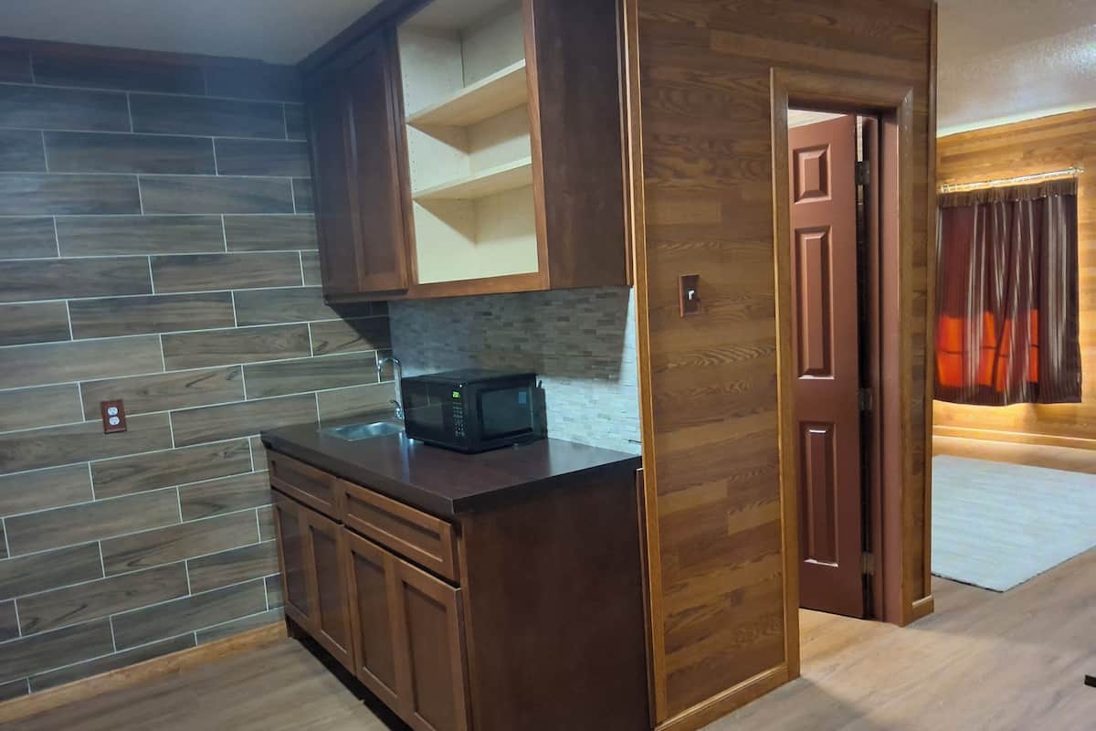 Una cocina con armarios de madera, un microondas y salpicadero de azulejos.