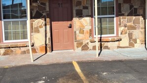 A building with a stone facade, a brown door, and two windows. - The Mint Motel (Arlington)