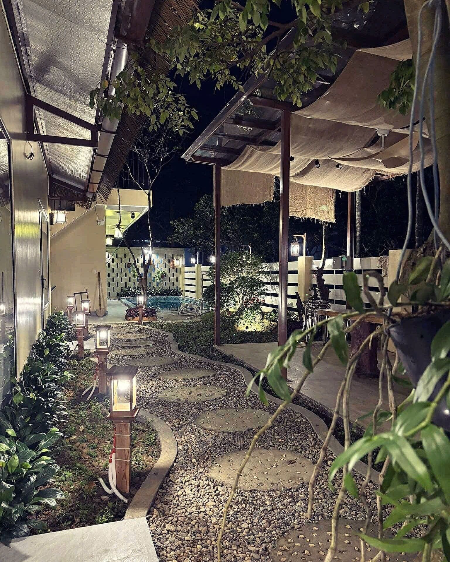 Un espacio al aire libre con piscina, rodeado de un sendero de grava y vegetación.