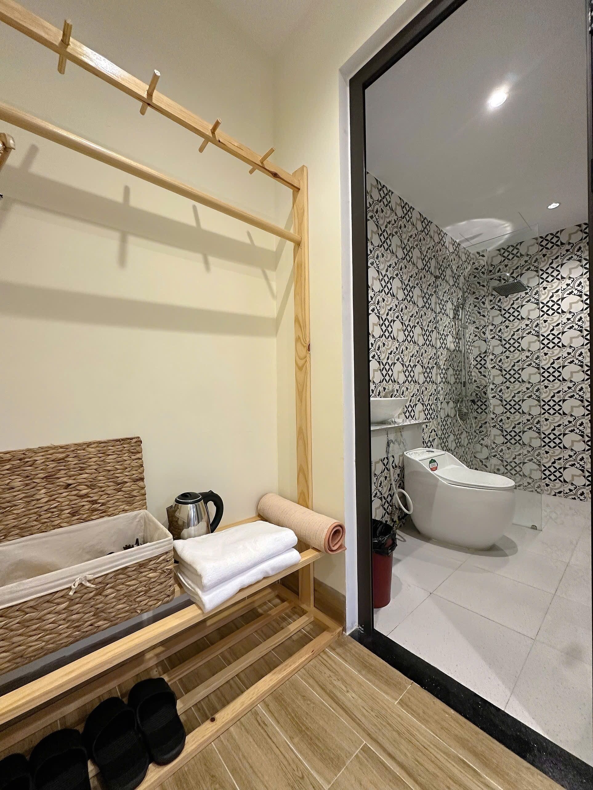 Ein Badezimmer mit Dusche, Toilette und einem Holzboden mit Handtüchern und Hausschuhen.