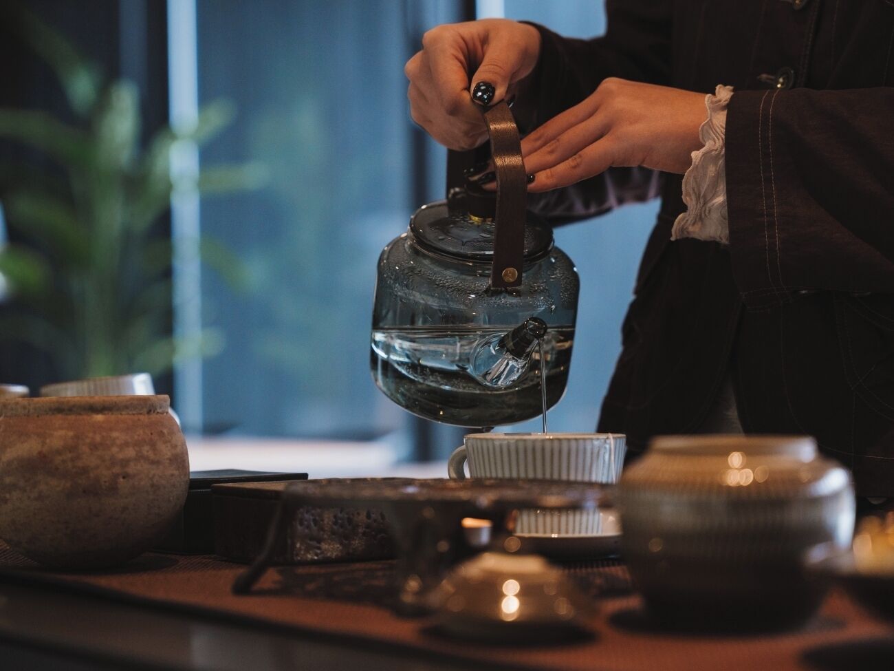 A person pouring tea from a teapot into a cup.