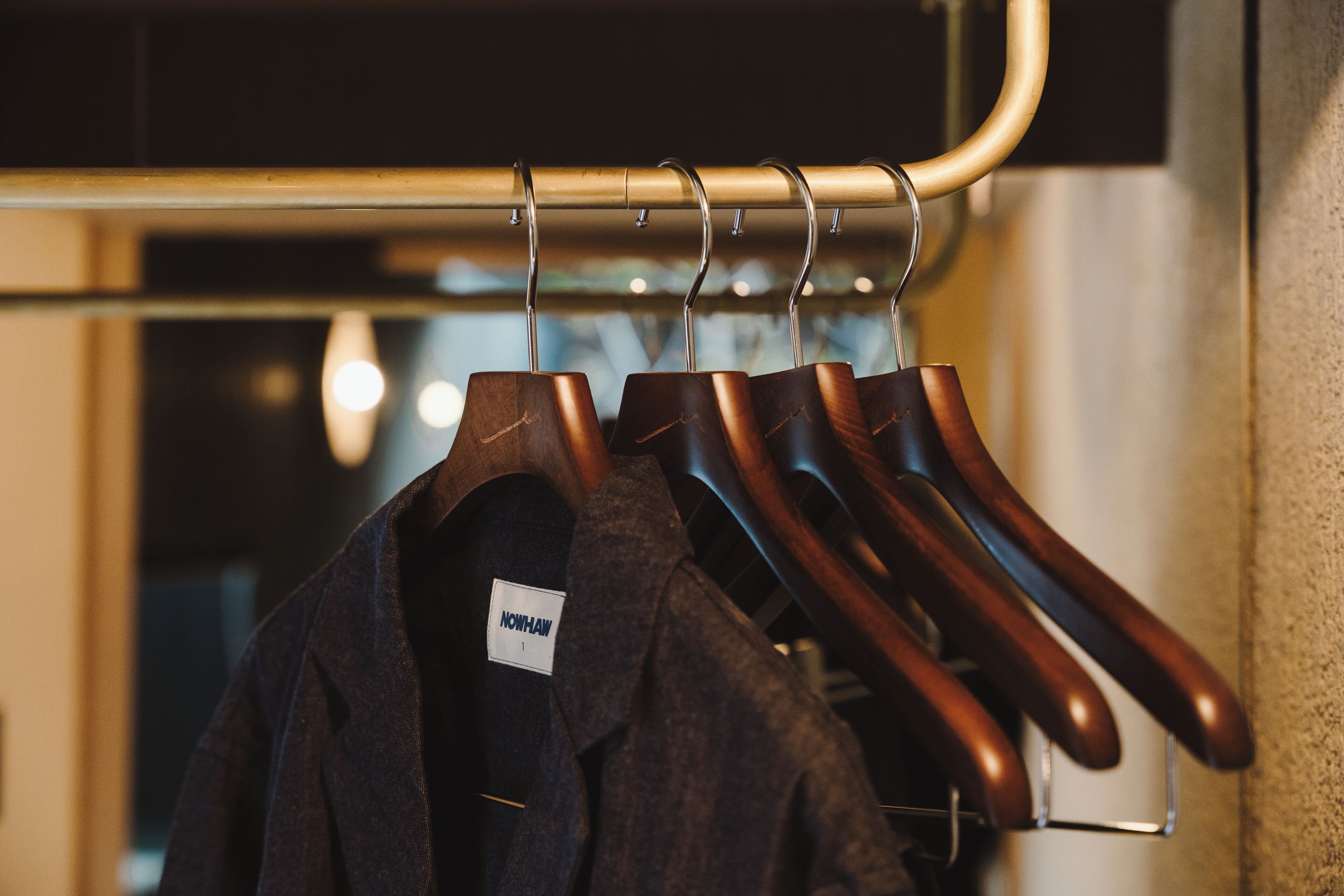 A clothing rack with several hangers holding dark-colored garments.