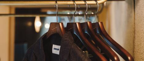 A clothing rack with several hangers holding dark-colored garments.