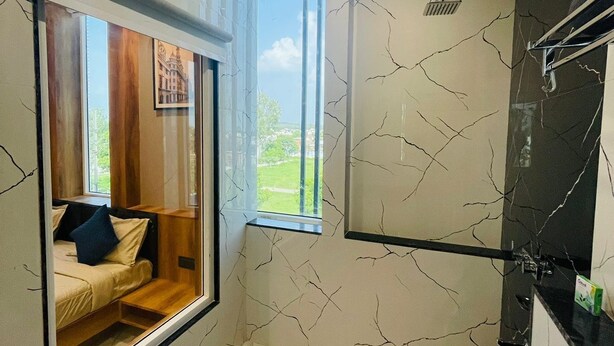 A modern bathroom with a built-in window, a shower, and a toilet. - Hotel The Golden Tree (Damoh)