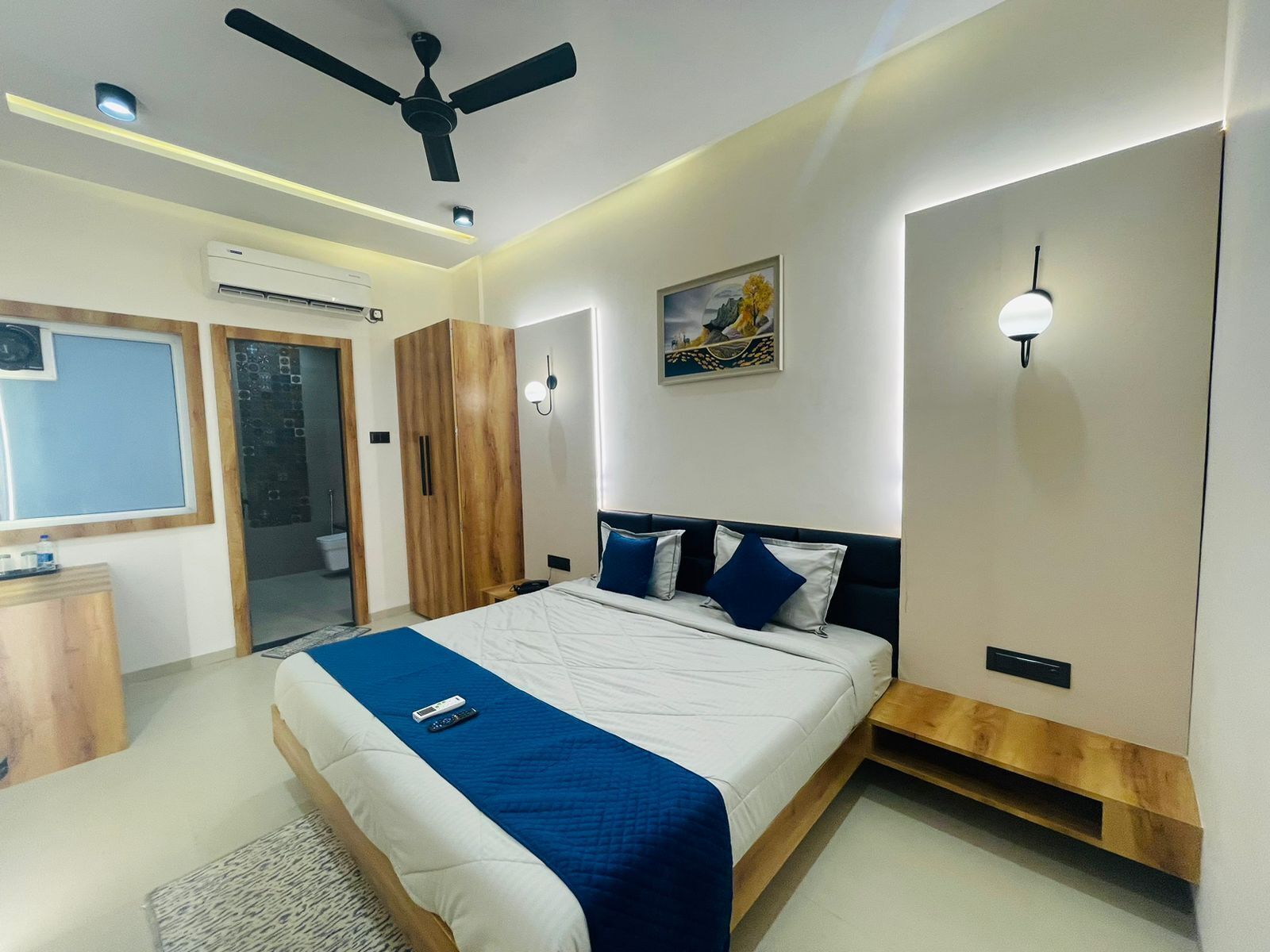 Un dormitorio con cama, ventilador de techo, aire acondicionado, armario y un cuadro en la pared.