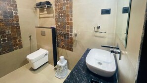 A bathroom with a toilet, a sink, a shower, and a mirror. - Hotel The Golden Tree (Damoh)