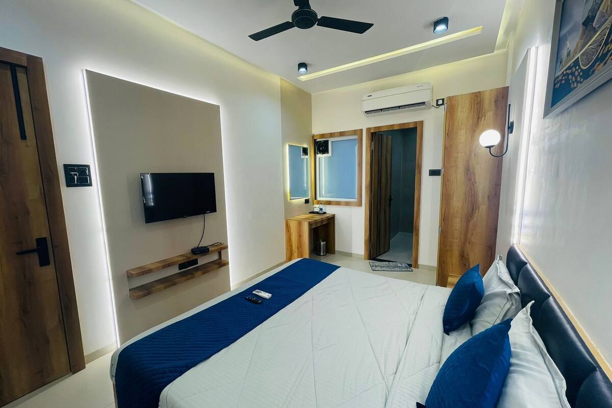 Ett modernt hotellrum med en säng, en TV, en takfläkt och en luftkonditioneringsanläggning.