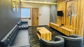 A modern lounge area with a sofa, a wooden coffee table, and a seating bench. - Hotel The Golden Tree (Damoh)