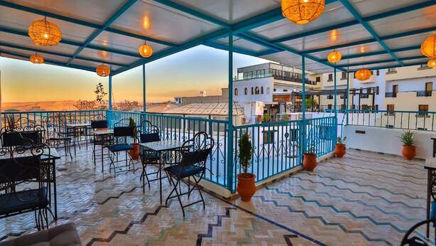A rooftop terrace with outdoor seating, blue railings, and hanging lanterns. - dar fes flower (Fès)
