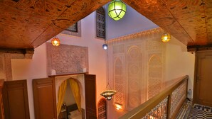 A traditional interior with ornate wooden ceilings, intricate wall designs, and a patterned floor. - dar fes flower (Fès)