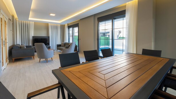 Un salon moderne avec une grande table en bois, des sièges confortables et un téléviseur.