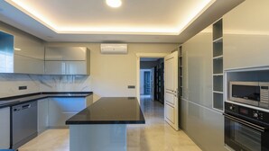 Une cuisine moderne dotée d’un îlot central, d’appareils électroménagers en acier inoxydable et d’un design épuré.