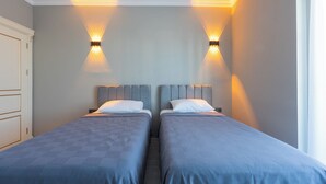 Une chambre d’hôtel avec deux lits, chacun doté d’une tête de lit et d’un oreiller. Des lampes murales sont fixées au-dessus de chaque lit.