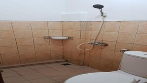 A small bathroom with a toilet, a shower, and a sink. - Hotel Cemara Gading (Dramaga)