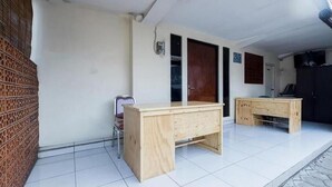 A room with a wooden desk, a chair, and a small table. There is a door and a window in the background. - Hotel Cemara Gading (Dramaga)