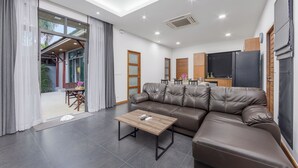 A modern living room with a leather sofa, a wooden coffee table, and a ceiling fan. - Villa Kiana Private Pool 10 min Nai Harn (Rawai)